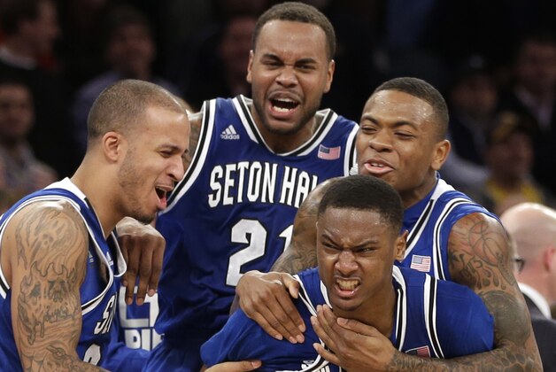 Teammates mob Seton Hall's Sterling Gibbs (4) after he hit the winning shot during the second half of an NCAA men's college basketball game against Villanova in the second round of the Big East tournament at Madison Square Garden, Thursday, March 13, 2014 in New York. Seton Hall defeated Villanova 64-63.(AP Photo/Seth Wenig)
