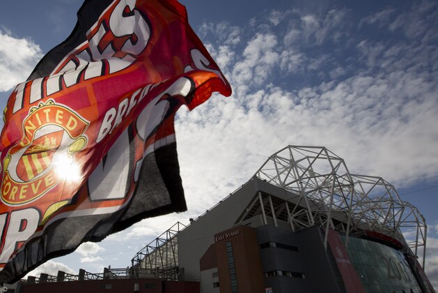 A flag is held outside Old Trafford Stadium before Manchester United's parade across Manchester, after winning the English Premier League, Manchester, England, Monday May 13, 2013. Manager Alex Ferguson will retire at the end of the season after more than 26 years in charge at the club. (AP Photo/Jon Super)