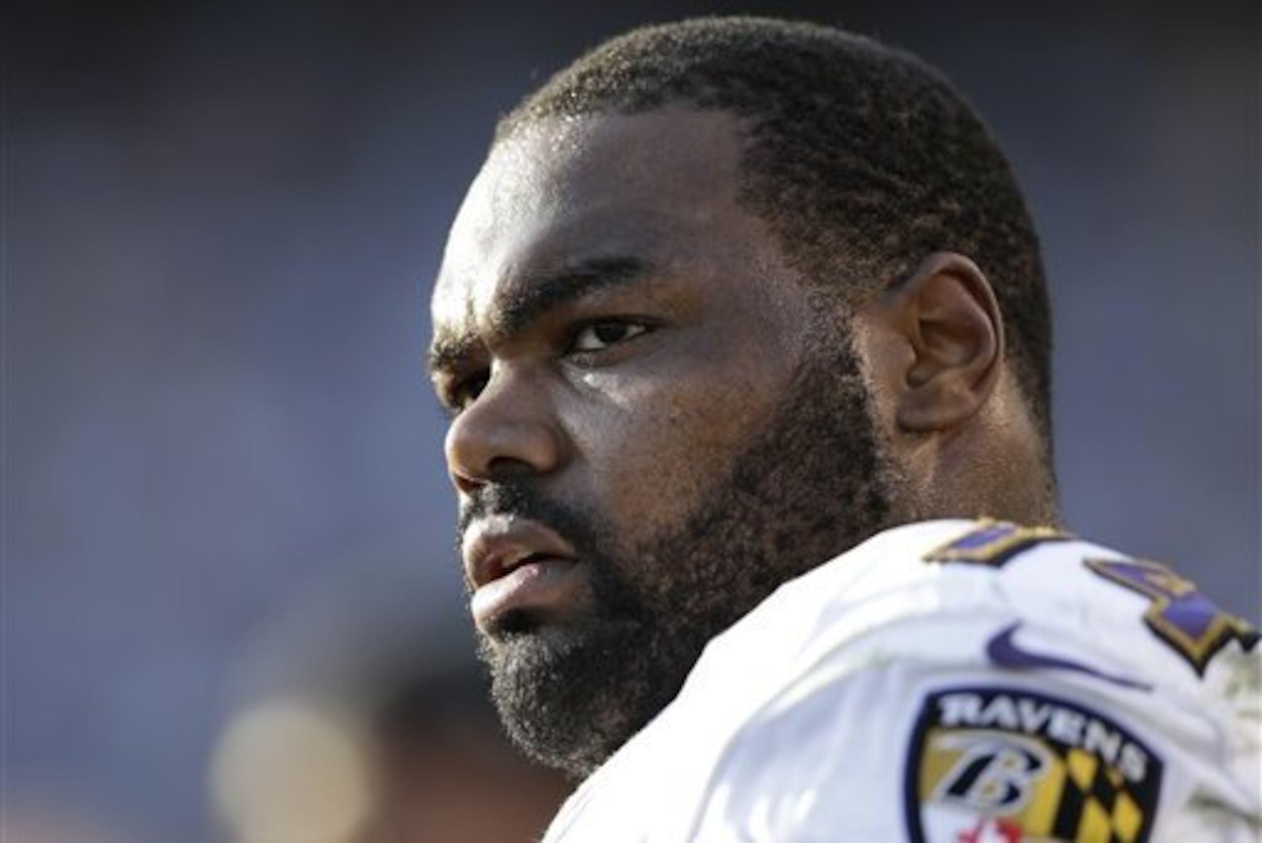 In this Nov. 25, 2012 photo, Baltimore Ravens tackle Michael Oher sits on the sidelines during the second half of an NFL football game against the San Diego Chargers, in San Diego. Oher and his adoptive family were depicted in the book and movie,