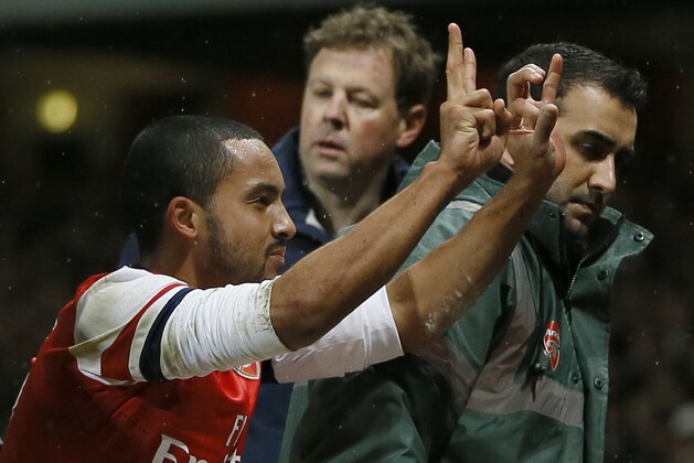 Arsenal's Theo Walcott gestures to the crowd to show the score of 2-0, as he is stretchered off in front of Tottenham fans during the English FA Cup third round soccer match between Arsenal and Tottenham Hotspur at the Emirates Stadium in London, Saturday, Jan. 4, 2014. Arsenal won the match 2-0.  (AP Photo/Kirsty Wigglesworth)