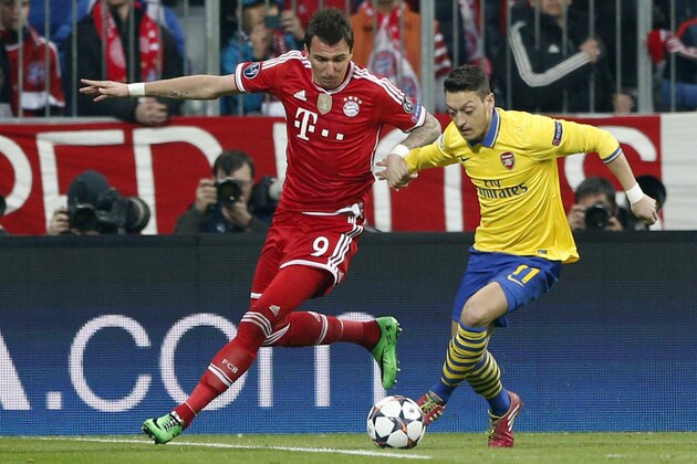 Bayern's Mario Mandzukic, left, and Arsenal's Mesut Ozil challenge for the ball during the Champions League round of 16 second leg soccer match between FC Bayern Munich and FC Arsenal in Munich, Germany, Tuesday, March 11, 2014. (AP Photo/Matthias Schrader)