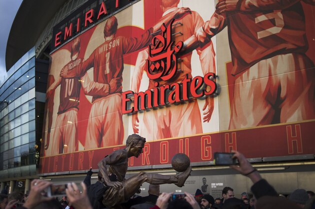 Fans gather around the statue of former Arsenal player Dennis Bergkamp, in front of the Emirates Stadium, in London, Saturday, Feb. 22, 2014. (AP Photo/Bogdan Maran)