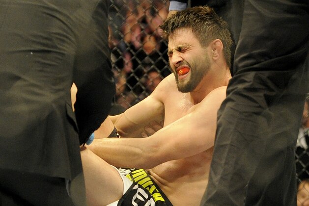 Carlos Condit is tended to by doctors after being injured during a UFC 171 mixed martial arts welterweight bout against Tyron Woodley, Saturday, March. 15, 2014, in Dallas. Woodley won by TKO. (AP Photo/Matt Strasen)