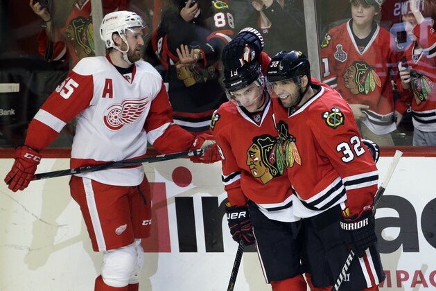 Chicago Blackhawks' Jonathan Toews (19) celebrates with Michal Rozsival (32) after scoring his goal as Detroit Red Wings' Niklas Kronwall (55) reacts during the third period of an NHL hockey game in Chicago, Sunday, March 16, 2014. The Blackhawks won 4-1. (AP Photo/Nam Y. Huh)