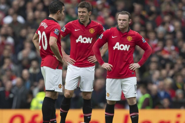 Manchester United's Wayne Rooney, right, Michael Carrick, centre, and Robin van Persie wait for play to restart after Liverpool's first goal during their English Premier League soccer match at Old Trafford Stadium, Manchester, England, Sunday March 16, 2014. Liverpool won the game 3-0. (AP Photo/Jon Super)