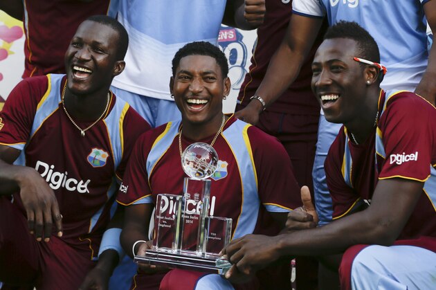 West Indies' Darren Sammy, left,  Krishmar Santokie, center, and Andre Russell, pose with the trophy after beating England 2-1, in the series of three T20 International cricket matches at the Kensington Oval in Bridgetown, Barbados, Thursday, March 13, 2014. (AP Photo/Ricardo Mazalan)