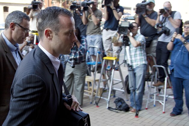 Oscar Pistorius, right accompanied by relative, arrives at the high court in Pretoria, South Africa, Tuesday, March 18, 2014. Pistorius is charged with murder for the shooting death of his girlfriend, Reeva Steenkamp, on Valentines Day in 2013. (AP Photo/Themba Hadebe)