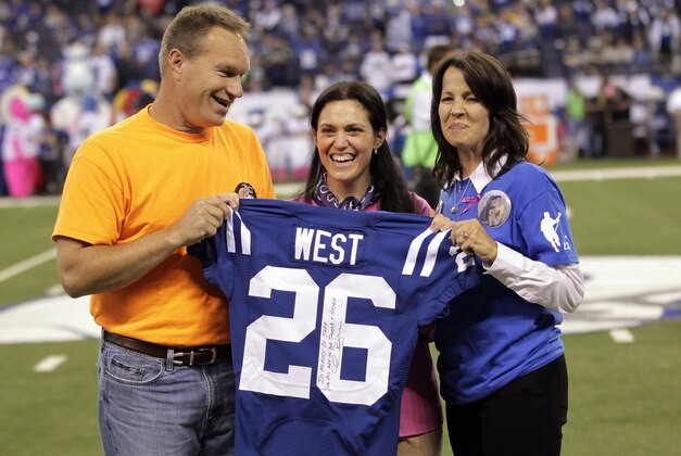 Indianapolis Colts vice chair/owner Carlie Irsay-Gordon, center, presents a jersey to Scott West, left, and his wife Julie West, right, during halftime of an NFL football game between the Colts and the Seattle Seahawks in Indianapolis, Sunday, Oct. 6, 2013. The West's son Jake West, a 17-year-old LaPorte High School student, collapsed during football practice and later died of an enlarged heart on Sept. 25. (AP Photo/AJ Mast)