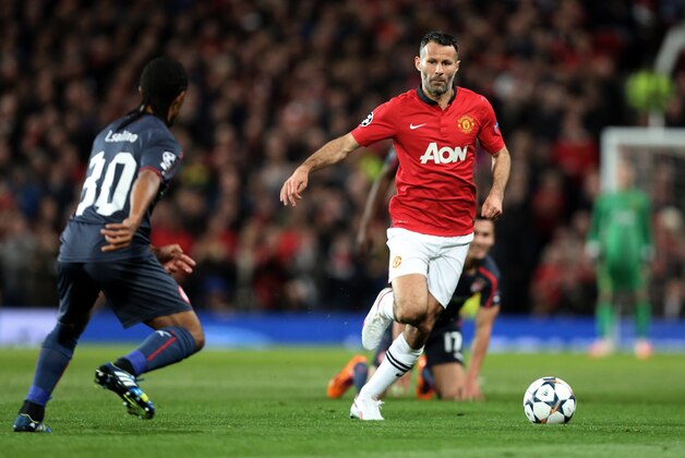 Olympiakos' Leandro Salino, left, competes for the ball with Manchester United's Ryan Giggs during their Champions League last 16 second leg soccer match at Old Trafford Stadium, Manchester, England, Wednesday, March 19, 2014. (AP Photo/Jon Super)