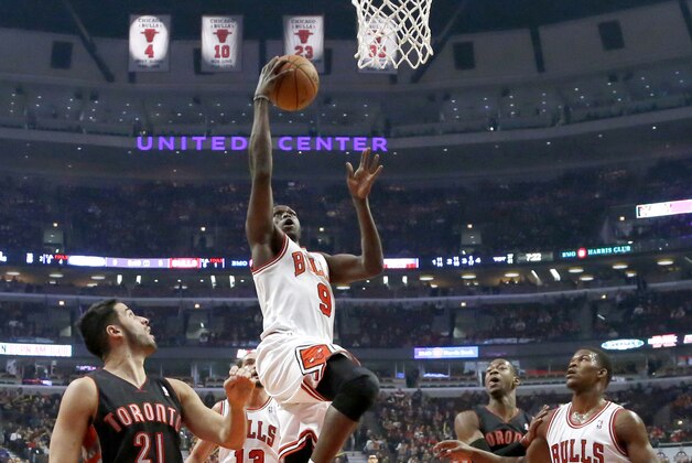 Chicago Bulls small forward Luol Deng (9) drives to the basket past Toronto Raptors point guard Greivis Vasquez, left, as Bulls' Jimmy Butler (21) and Raptors Terrence Ross stand near during the first half of an NBA basketball game Tuesday, Dec. 31, 2013, in Chicago. (AP Photo/Charles Rex Arbogast)
