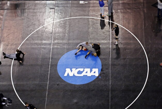 Donald Patrick, left, of Davidson College in Davidson, N.C., works with his coach, Brandon Sinnott, right, on a wrestling mat in Oklahoma City, Wednesday, March 19, 2014, in preparation for the NCAA college wrestling championships. Competition begins March 20. (AP Photo/Sue Ogrocki)