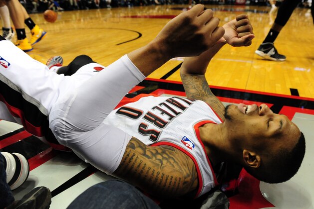 Mar 16, 2014; Portland, OR, USA; Portland Trail Blazers guard Damian Lillard (0) lays on the court after missing a shot  during the fourth quarter of the game against the Golden State Warriors at the Moda Center. The Warriors won the game 113-112. Mandatory Credit: Steve Dykes-USA TODAY Sports