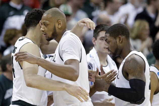 Michigan State's Adreian Payne, center, and Branden Dawson, right, are greeted with hugs as they head to the bench in the final moments of the second half during the second round of the NCAA men's college basketball tournament against Delaware in Spokane, Wash., Thursday, March 20, 2014. Michigan State won 93-78. (AP Photo/Elaine Thompson)