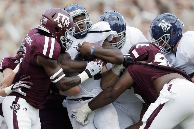 Rice's Charles Ross, center, is hit by Texas A&M defenders Tommy Sanders, left, and Isaiah Golden, right, as he works to cross the goal line for a touchdown during the fourth quarter of an NCAA college football game, Saturday,  Aug. 31, 2013, in College Station, Texas.  (AP Photo/Eric Gay)