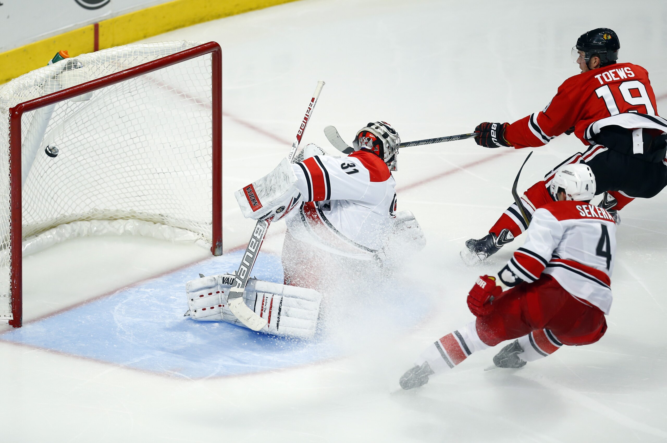 Chicago Blackhawks center Jonathan Toews (19) gets the puck past Carolina Hurricanes goalie Anton Khudobin (31) for a goal as Hurricanes defenseman Andrej Sekera (4) trails the play during the third period of an NHL hockey game in Chicago, Friday, March 21, 2014. The Blackhawks won 3-2. (AP Photo/Jeff Haynes)