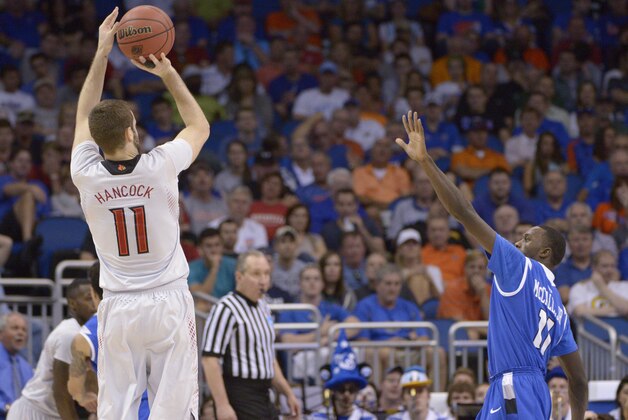 Louisville forward Luke Hancock (11) aims for a three-point basket as Saint Louis guard Mike McCall Jr. (11) defends, during the first half in a third-round game in the NCAA college basketball tournament  Saturday, March 22, 2014, in Orlando, Fla. (AP Photo/Phelan M. Ebenhack)