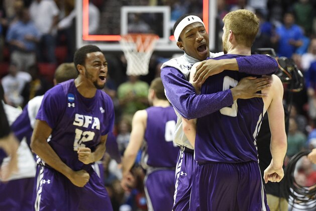 Stephen F. Austin forward Ben Brown-White, second from right, hugs teammate guard Thomas Walkup, right, after defeating Virginia Commonwealth 77-75 in overtime in a second-round game in the NCAA college basketball tournament Friday, March 21, 2014, in San Diego. (AP Photo/Denis Poroy)