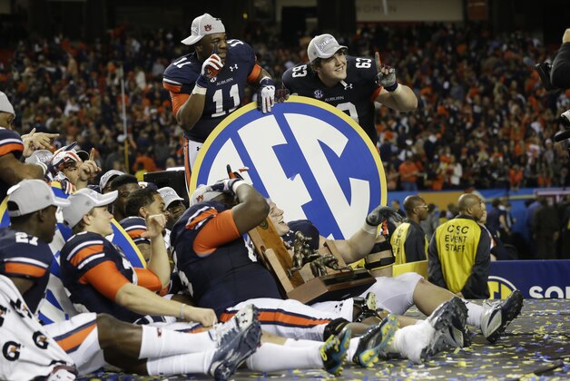 Auburn players [pose for cameras after the second half of the Southeastern Conference NCAA football championship game against the Missouri, Saturday, Dec. 7, 2013, in Atlanta. Auburn won 59-42. (AP Photo/Dave Martin)