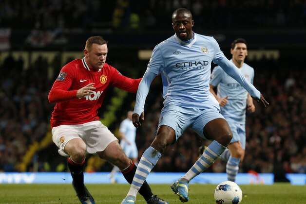 Manchester City's Yaya Toure, right, competes for the ball with Manchester United's Wayne Rooney during the English Premier League soccer match between Manchester City and Manchester United at the Etihad Stadium in Manchester, Monday, April 30, 2012.  (AP Photo/Matt Dunham)