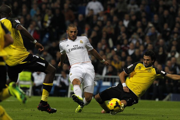 Real Madrid's Karim Benzema, centre, from France,   scores past Sevilla's Stephane M'Bia, from Cameron, and Nicolas Pareja, right, from Argentina, his side's fourth goal during a Spanish La Liga soccer match between Real Madrid and Sevilla at the Santiago Bernabeu stadium in Madrid, Spain, Wednesday Oct. 30, 2013. (AP Photo/Francisco Seco)