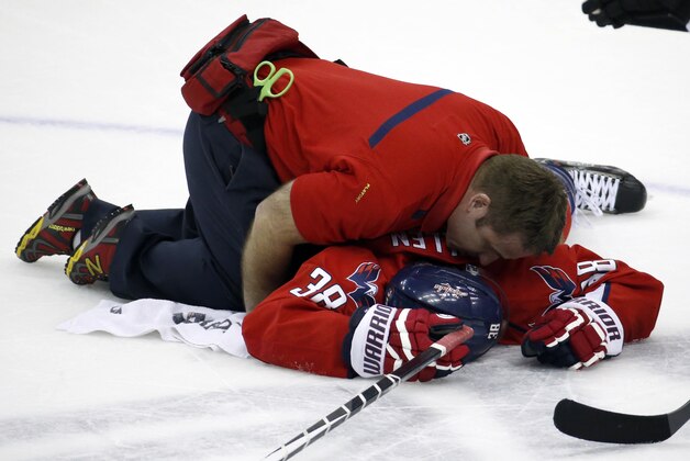 Washington Capitals trainer Greg Smith tends to defenseman Jack Hillen, after Hillen's collision with right wing Alex Ovechkin (8), from Russia, in the overtime portion of an NHL hockey game against the Los Angeles Kings, Tuesday, March 25, 2014, in Washington. The Kings won 5-4 in a shootout. (AP Photo/Alex Brandon)