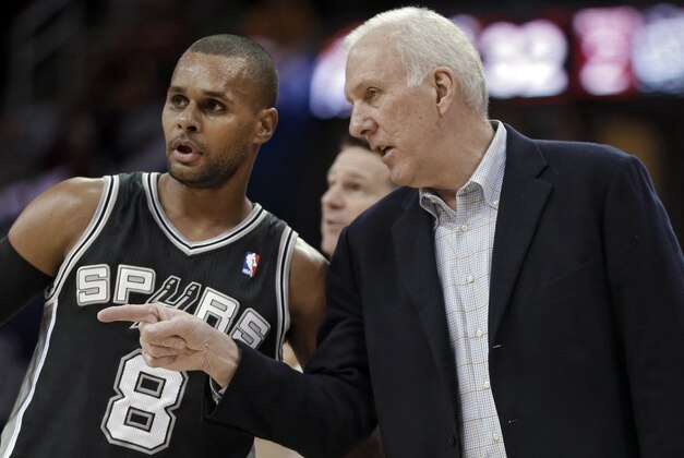 San Antonio Spurs coach Gregg Popovich talks to Patty Mills during the second quarter of an NBA basketball game against the Cleveland Cavaliers on Tuesday, March 4, 2014, in Cleveland. (AP Photo/Mark Duncan)