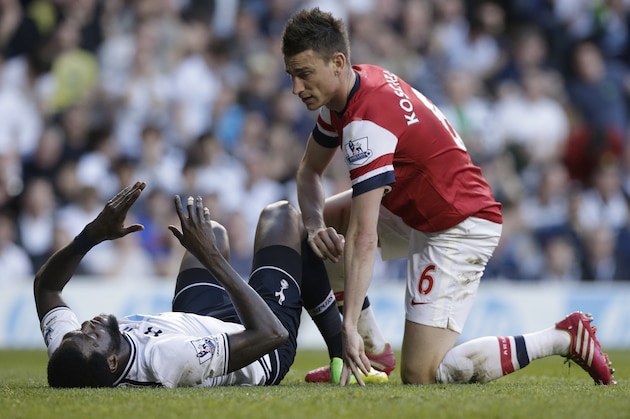 Tottenham Hotspur's Emmanuel Adebayor lies on the ground following a tackle by Arsenal's Laurent Koscielny during the English Premier League soccer match between Tottenham Hotspur and Arsenal at White Hart Lane stadium in London, Sunday, March 16, 2014. (AP Photo/Matt Dunham)