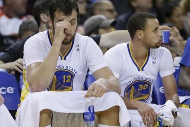 Golden State Warriors center Andrew Bogut, left, and guard Stephen Curry, right, rest on the bench during the third quarter of their NBA basketball game against the San Antonio Spurs Saturday, March 22, 2014, in Oakland, Calif. San Antonio won the game 99-90. (AP Photo/Eric Risberg)
