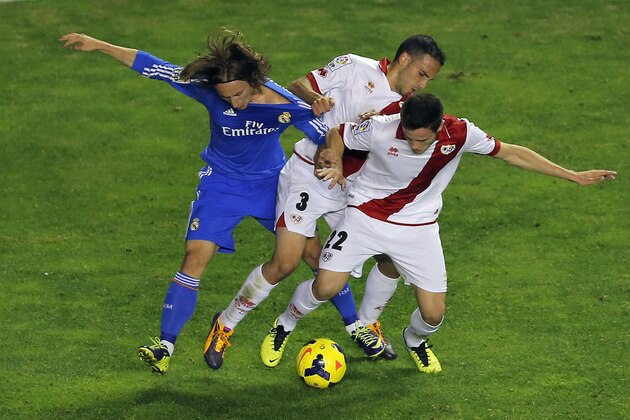 Real Madrid's Luka Modric, left, vies for the ball with Rayo Vallecano's Nacho, center, and Saul Niguez, right, during a Spanish La Liga soccer match at the Vallecas stadium in Madrid, Spain, Saturday, Nov. 2, 2013. (AP Photo/Andres Kudacki)