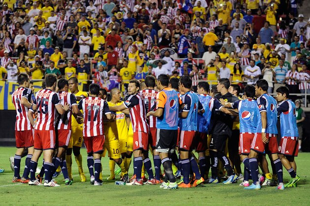 Chivas and Club America team members gather on the field after a fight between two players during the first half of the El Super Clasico soccer match on Wednesday, July 3, 2013 in Las Vegas. Two players from each team were ejected after the brief scuffle. Chivas won the game 1-0. (AP Photo/David Becker)