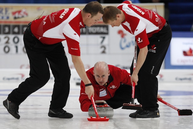 Canada's skip Kevin Koe, center, releases a stone as first Nolan Thiessen, left, and second Carter Rycroft sweep during their gold medal match against Norway, at the Curling World Championships, in Cortina D'Ampezzo, Italy, Sunday, April 11, 2010. Canada won the match. (AP Photo/Antonio Calanni)