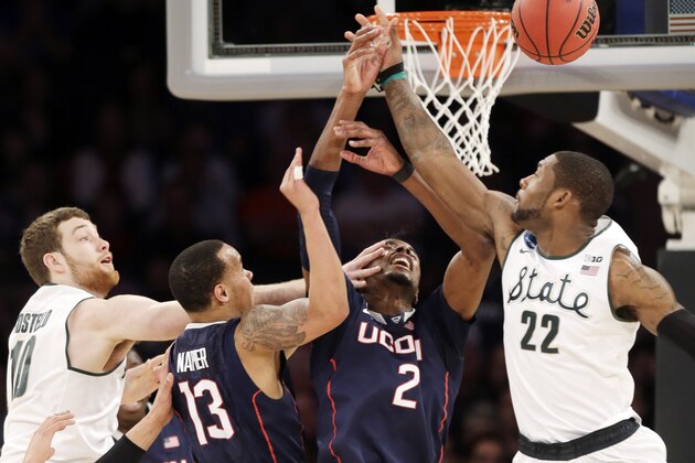 Michigan State's Matt Costello, left, and teammate Branden Dawson, right, battle under the basket with Connecticut's Shabazz Napier (13) and DeAndre Daniels in the first half of a regional final at the NCAA college basketball tournament on Sunday, March 30, 2014, in New York. (AP Photo/Seth Wenig)