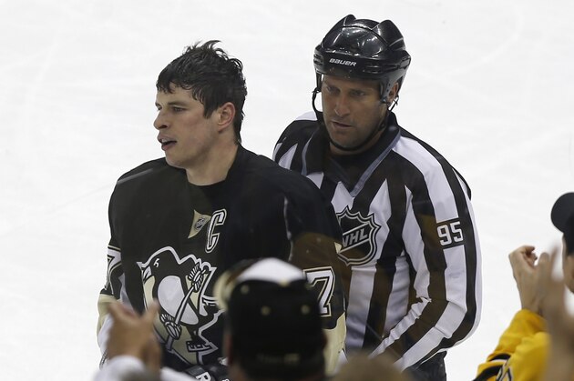 Fans applaud as Pittsburgh Penguins' Sidney Crosby is escorted to the penalty box after being penalized 2 minutes for roughing during the third period of an NHL hockey game against the Carolina Hurricanes on Tuesday, April 1, 2014, in Pittsburgh. The Hurricanes won 4-1.(AP Photo/Keith Srakocic)