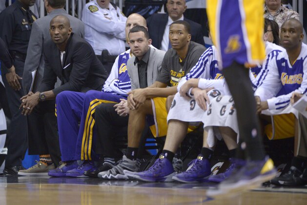 Los Angeles Lakers shooting guard Kobe Bryant, left, watches from the end of the bench as a teammate takes a shot during the first half of an NBA basketball game against the Orlando Magic in Orlando, Fla., Friday, Jan. 24, 2014.(AP Photo/Phelan M. Ebenhack)