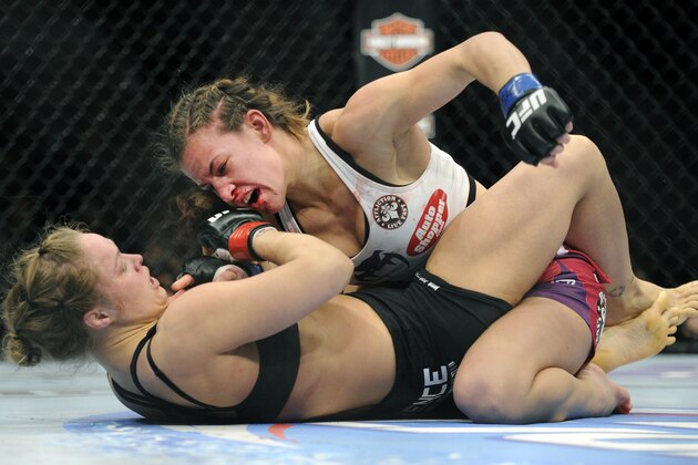 Miesha Tate, top, of Yakima, Wash., punches to Ronda Rousey of Venice, Calif., during the UFC 168 mixed martial arts middleweight championship bout during the UFC 168 mixed martial arts women's bantamweight title fight on Saturday, Dec. 28, 2013, in Las Vegas. Rousey won by a third round tap out. (AP Photo/David Becker)