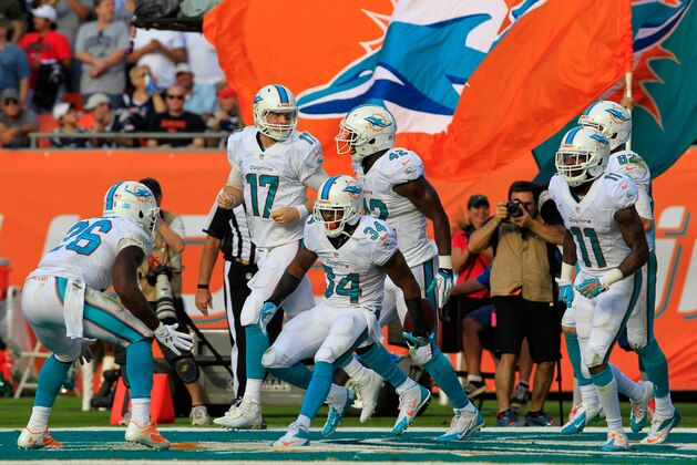 MIAMI GARDENS, FL - DECEMBER 15:  Marcus Thigpen #34 of the Miami Dolphins celebrates his touchdown in the fourth quarter with teammates  Ryan Tannehill #17 of the Miami Dolphins and  Lamar Miller #26 of the Miami Dolphins against the New England Patriots at Sun Life Stadium on December 15, 2013 in Miami Gardens, Florida.  (Photo by Chris Trotman/Getty Images)