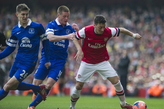 Arsenal's Mesut Özil, fights for the ball with Everton's John Stones and James McCarthy, during their FA Cup quarterfinal soccer match, at Emirates Stadium, in London, Saturday, March 8, 2014. (AP Photo/Bogdan Maran)
