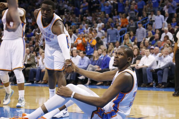 Oklahoma City Thunder forward Kevin Durant (35) is helped up by teammate Reggie Jackson (15) after falling in the second quarter of an NBA basketball game against the San Antonio Spurs in Oklahoma City, Thursday, April 3, 2014. (AP Photo/Sue Ogrocki)