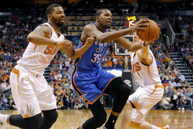 Oklahoma City Thunder forward Kevin Durant (35) drives between Phoenix Suns guard Goran Dragic, right, of Slovenia, and Markieff Morris during the first half of an NBA basketball game on Sunday, April 6, 2014,in Phoenix. (AP Photo/Matt York)