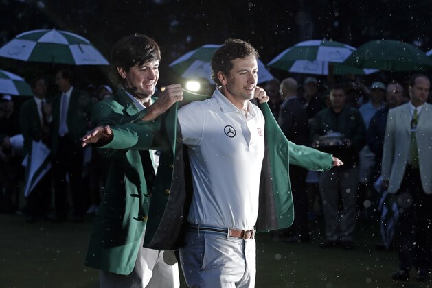 Bubba Watson, left, helps Adam Scott, of Australia, put on his green jacket after winning the Masters golf tournament Sunday, April 14, 2013, in Augusta, Ga. (AP Photo/Charlie Riedel)