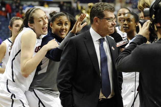 Connecticut's Breanna Stewart, left, and Kaleena Mosqueda-Lewis, center, sing Happy Birthday behind head coach Geno Auriemma, right, as he is interviewed on live television after their 87-44 win over Prairie View A&M in a first-round game of the NCAA women's college basketball tournament, Sunday, March 23, 2014, in Storrs, Conn. Today is Auriemma's 60th birthday. (AP Photo/Jessica Hill)