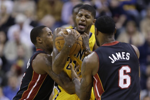 Indiana Pacers forward Paul George, center, is trapped by Miami Heat forward LeBron James, right, and guard Mario Chalmers in the first half of an NBA basketball game in Indianapolis, Tuesday, Dec. 10, 2013.  (AP Photo/Michael Conroy)