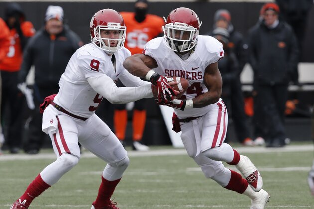 Oklahoma quarterback Trevor Knight (9) hands off to running back Brennan Clay (24) during an NCAA college football game between Oklahoma State and Oklahoma in Stillwater, Okla., Saturday, Dec. 7, 2013. (AP Photo/Sue Ogrocki)