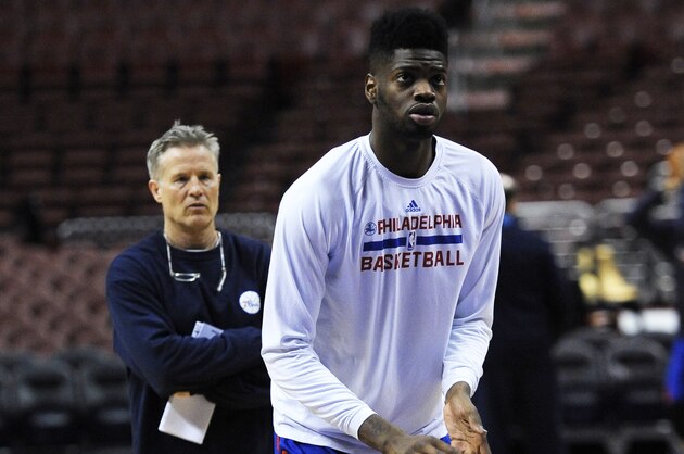 Philadelphia 76ers head coach Brett Brown, left, watches Nerlens Noel as he takes foul shots during warm ups before an NBA basketball against the Brooklyn Nets on Saturday, April 5, 2014, in Philadelphia. (AP Photo/Michael Perez)