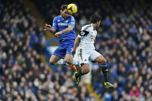 Chelsea's Branislav Ivanovic, left, jumps for the ball with a Swansea City player during their English Premier League soccer match at the Stamford Bridge ground in London, Thursday, Dec. 26, 2013. Chelsea won the match 1-0.(AP Photo/Lefteris Pitarakis)