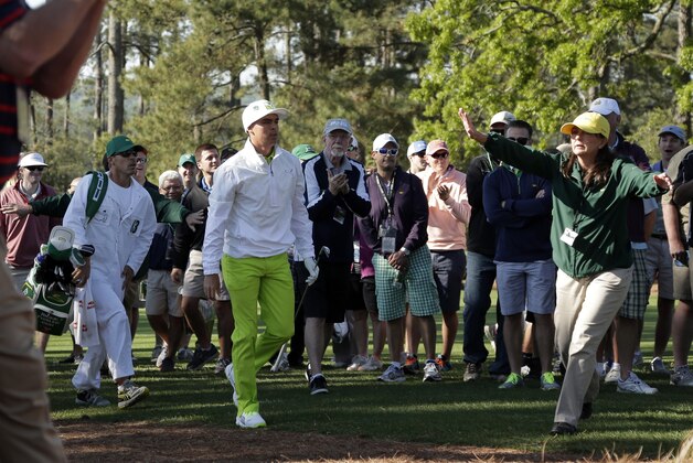 A course worker tries to stop spectators after Rickie Fowler hit out of the rough off the first fairway during the first round of the Masters golf tournament Thursday, April 10, 2014, in Augusta, Ga. (AP Photo/Charlie Riedel)