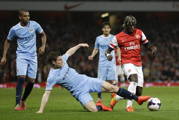 Arsenal's Bacary Sagna, right, vies for the ball with Manchester City's James Milner, bottom, during the English Premier League soccer match between Arsenal and Manchester City at the Emirates stadium in London, Saturday, March 29, 2014. (AP Photo/Kirsty Wigglesworth)