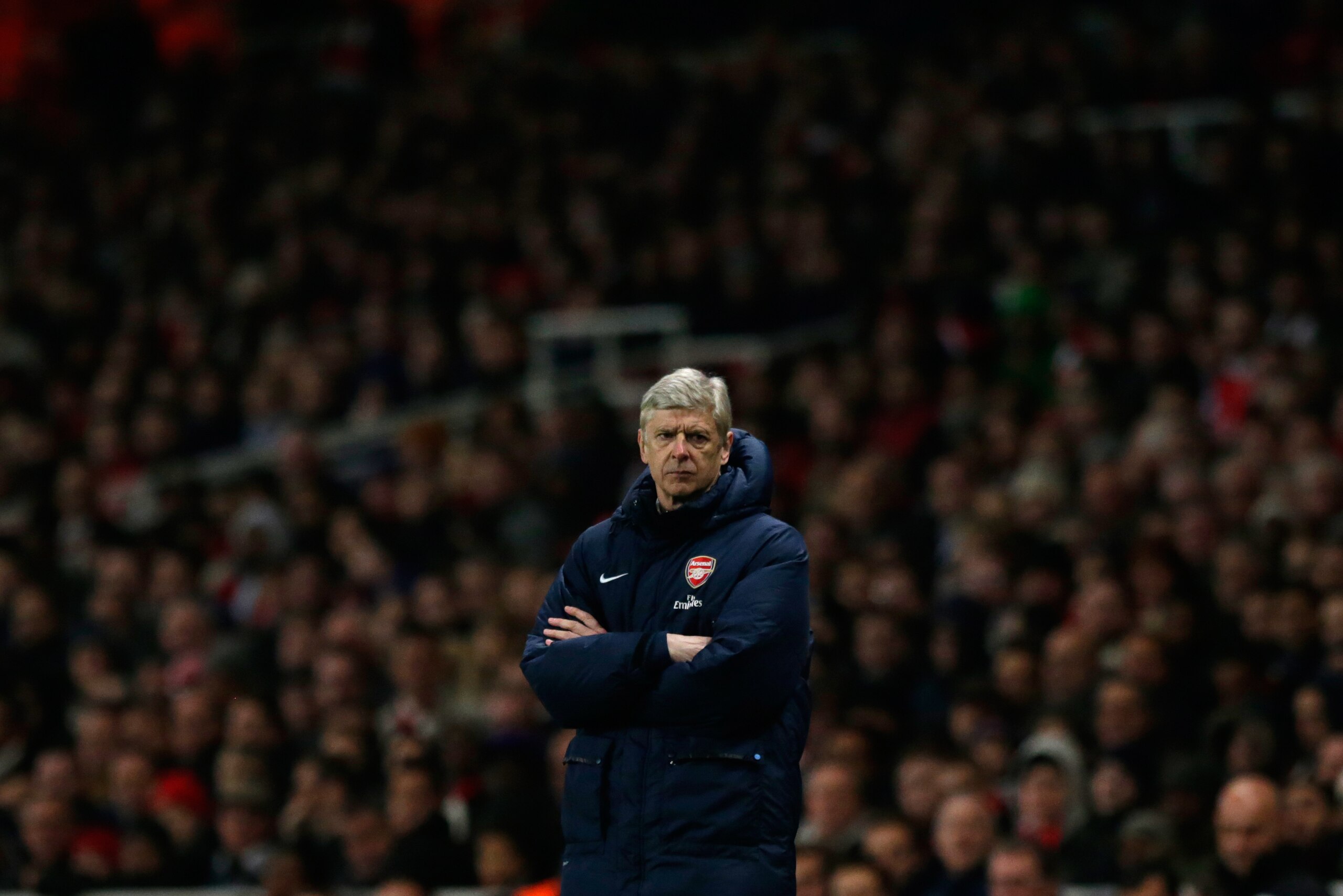 Arsenal's French manager Arsene Wenger stands with his arms folded during the English Premier League soccer match between Arsenal and Swansea City at the Emirates Stadium in London, Tuesday, March 25, 2014.  (AP Photo/Matt Dunham)