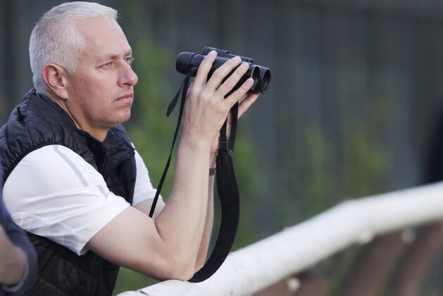 Trainer Todd Pletcher leans on the outside rail to watch his horses gallop on the track at Belmont Park during a morning workout Thursday, June 6, 2013 in Elmont, N.Y. Pletcher has five horses entered in Saturday's Belmont Stakes horse race. (AP Photo/Mark Lennihan)