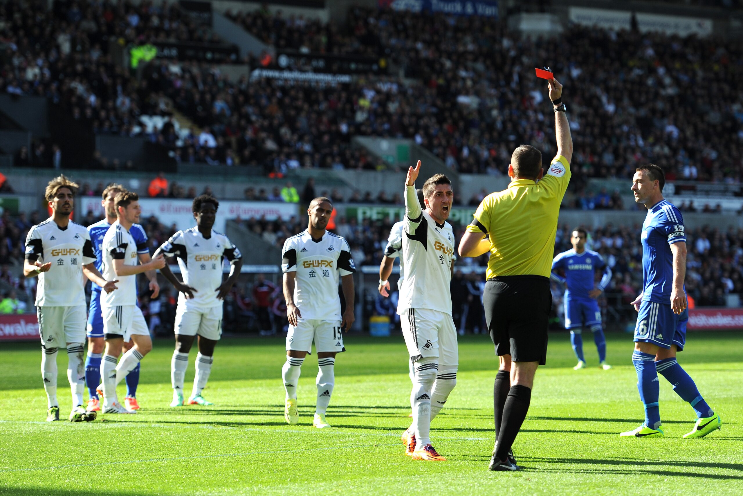 SWANSEA, WALES - APRIL 13:  Pablo Hernandez of Swansea remonstrates with Referee Phil Dowd as he shows the red card to Chico Flores (L) of Swansea during the Barclays Premier League match between Swansea City and Chelsea at Liberty Stadium on April 13, 2014 in Swansea, Wales.  (Photo by Chris Brunskill/Getty Images)